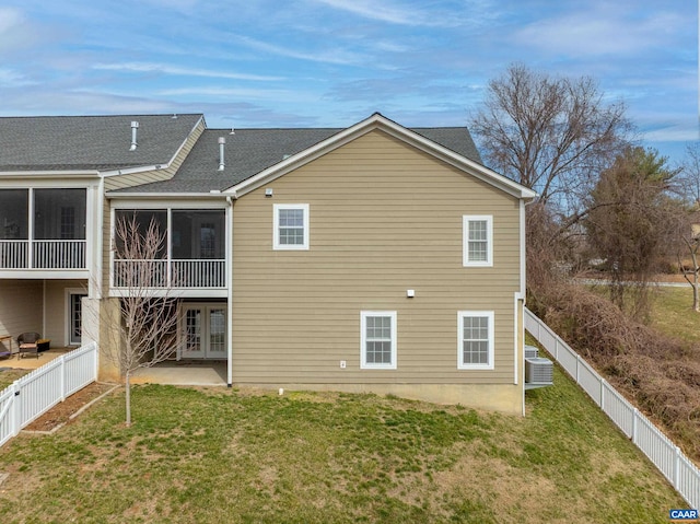 back of property with french doors, cooling unit, a sunroom, a lawn, and a fenced backyard