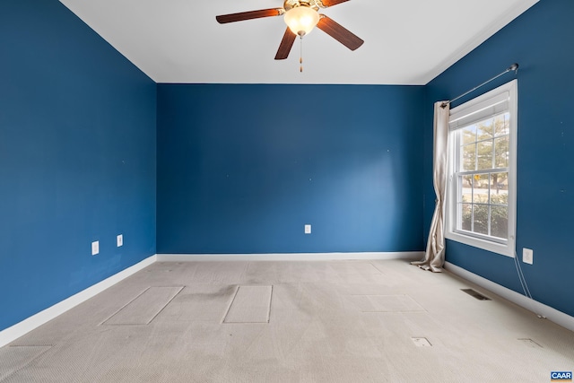 carpeted empty room featuring baseboards, visible vents, and ceiling fan