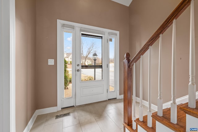 foyer with light tile patterned floors, stairway, visible vents, and baseboards