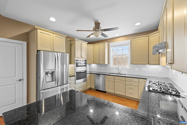 kitchen featuring a ceiling fan, a sink, under cabinet range hood, appliances with stainless steel finishes, and tasteful backsplash