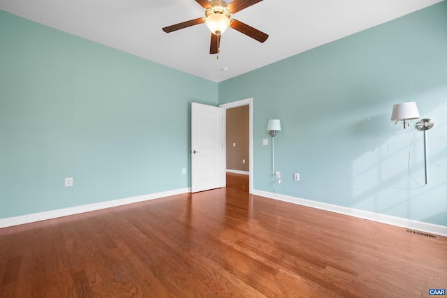 empty room featuring visible vents, wood finished floors, baseboards, and ceiling fan