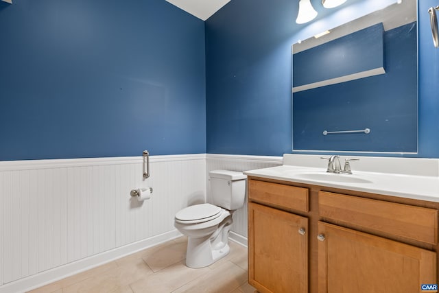 bathroom featuring toilet, tile patterned flooring, wainscoting, and vanity