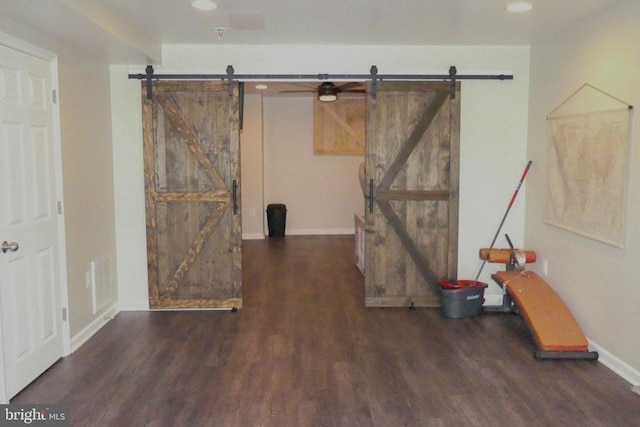 interior space with a barn door, wood finished floors, baseboards, and recessed lighting