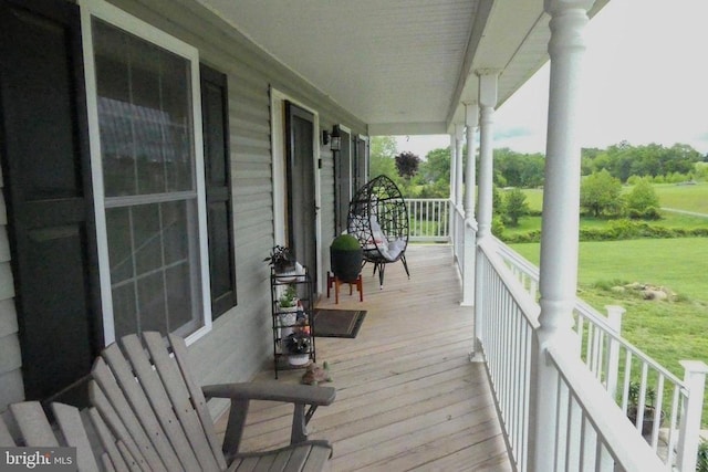 wooden deck with a porch and a lawn