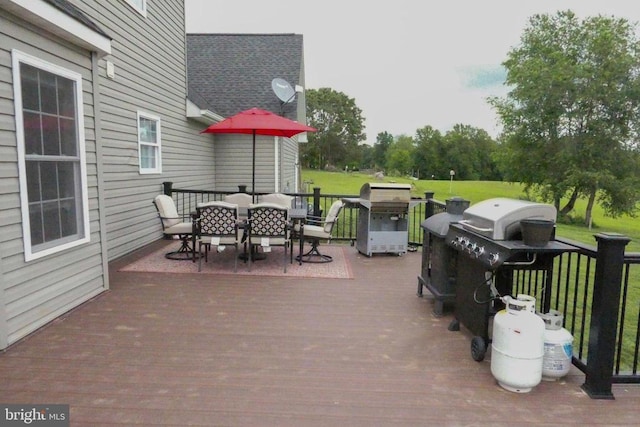 deck featuring outdoor dining area, a grill, and a lawn