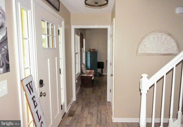 foyer entrance with wood finished floors, stairway, and baseboards