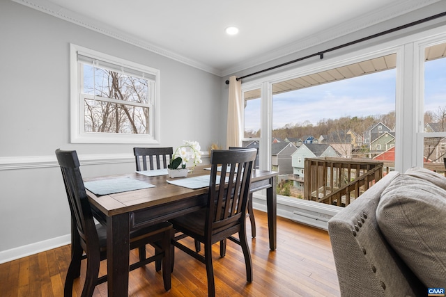 dining space with hardwood / wood-style flooring, ornamental molding, baseboards, and plenty of natural light