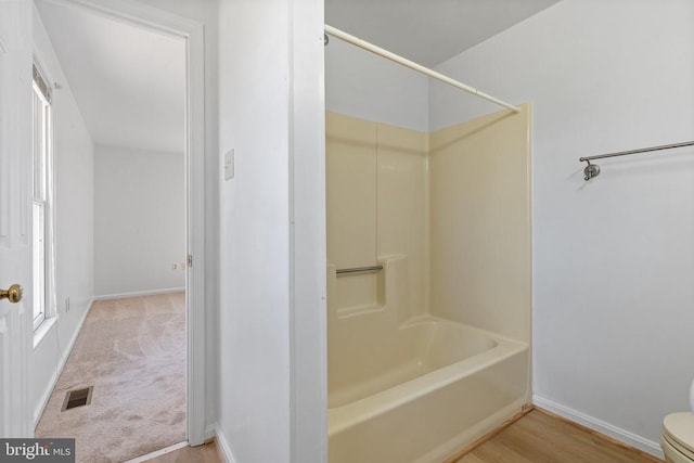 full bathroom with baseboards, toilet, washtub / shower combination, and wood finished floors
