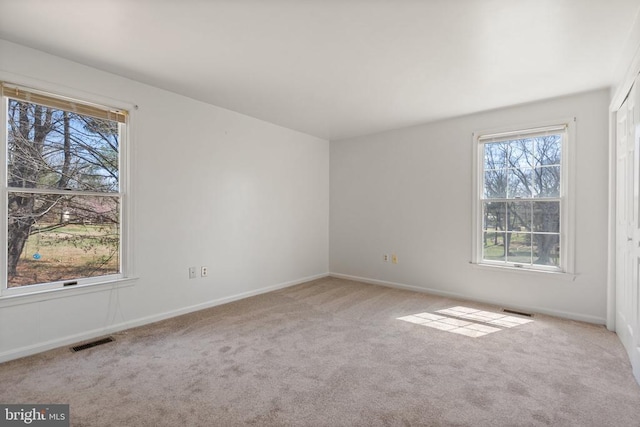 unfurnished room featuring healthy amount of natural light, carpet, and baseboards