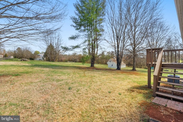 view of green lawn featuring an outbuilding, a storage unit, and a wooden deck