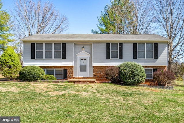 raised ranch featuring brick siding and a front lawn