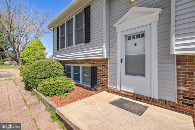 entrance to property with brick siding and a patio area