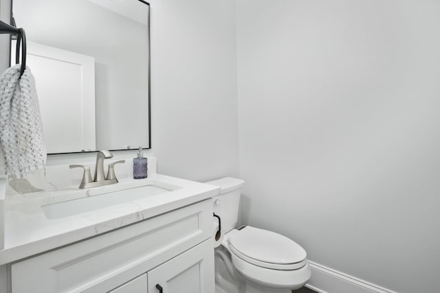 bathroom with baseboards, vanity, and toilet