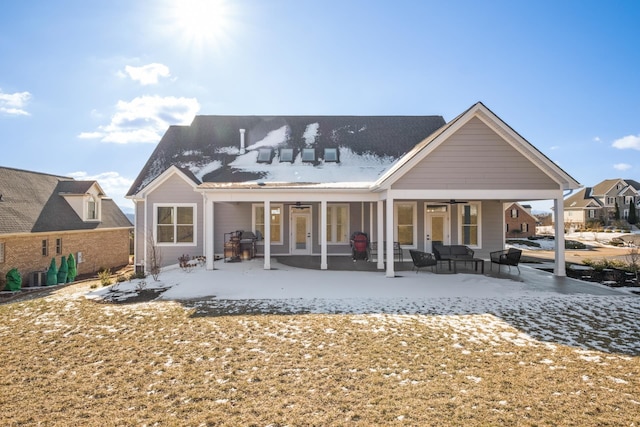 snow covered house with a patio, outdoor lounge area, and a ceiling fan