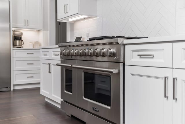 kitchen with stainless steel appliances, light countertops, dark wood finished floors, and white cabinets