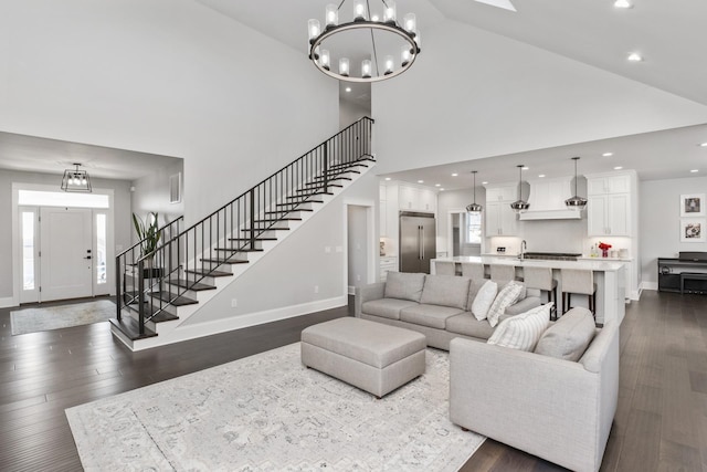 living room featuring baseboards, stairway, dark wood-type flooring, an inviting chandelier, and recessed lighting