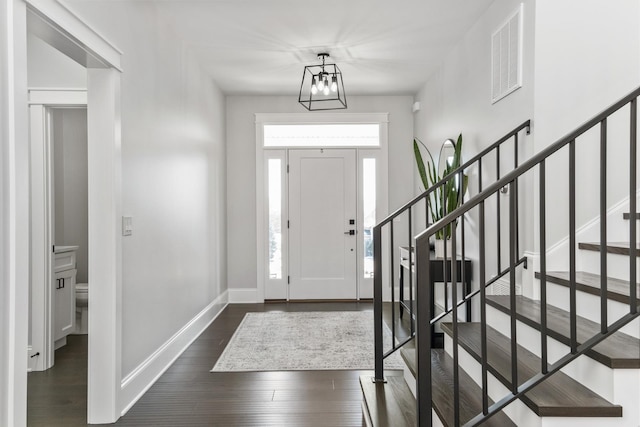 foyer featuring visible vents, dark wood finished floors, stairway, and baseboards