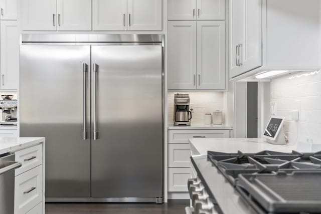 kitchen featuring appliances with stainless steel finishes, backsplash, light stone counters, and white cabinets