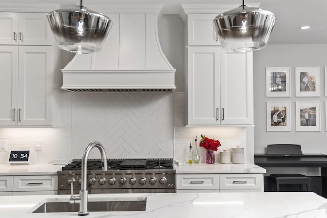 kitchen featuring stainless steel stove, light stone countertops, white cabinetry, custom exhaust hood, and decorative backsplash