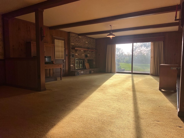 unfurnished living room featuring carpet, wooden walls, a fireplace, and beamed ceiling