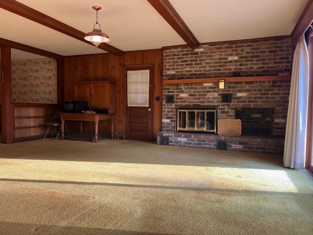 unfurnished living room with wooden walls, a fireplace, beam ceiling, and carpet floors