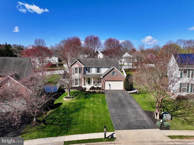 traditional home featuring driveway, a porch, brick siding, and a front yard