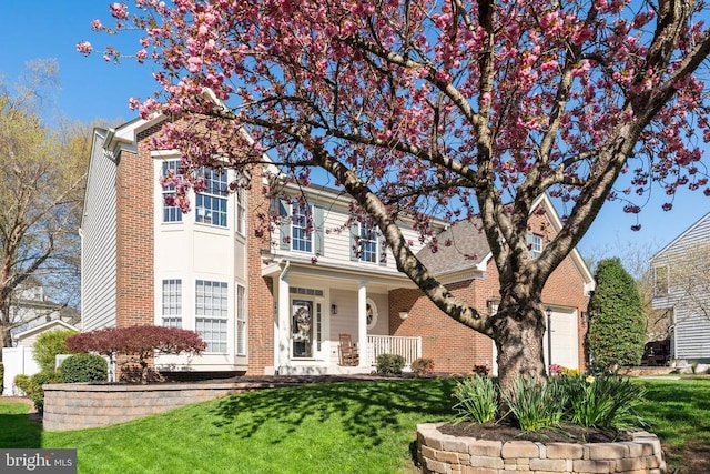 traditional home with a front yard, brick siding, and a porch