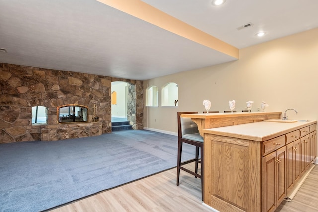 3417 Lake Pointe Dr, Rockingham, VA 22801 - kitchen featuring arched walkways, open floor plan, a stone fireplace, a breakfast bar area, and light wood-type flooring