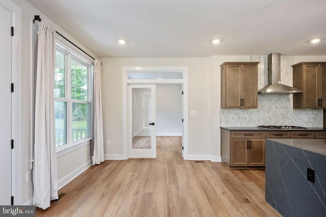 11207 Redlands Trl, Spotsylvania, VA 22551 - kitchen with wall chimney exhaust hood, dark countertops, light wood-type flooring, tasteful backsplash, and baseboards