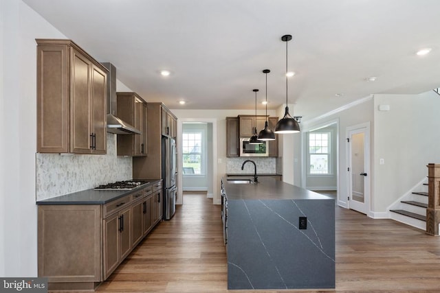 11207 Redlands Trl, Spotsylvania, VA 22551 - kitchen with dark countertops, appliances with stainless steel finishes, wall chimney exhaust hood, light wood-style flooring, and backsplash
