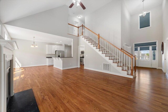239 Windsor Dr, Fishersville, VA 22939 - unfurnished living room featuring high vaulted ceiling, stairs, a ceiling fan, wood finished floors, and a chandelier