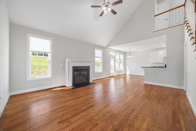 239 Windsor Dr, Fishersville, VA 22939 - unfurnished living room featuring a fireplace with flush hearth, ceiling fan, wood finished floors, high vaulted ceiling, and a chandelier