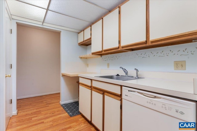 kitchen with light countertops, a sink, baseboards, dishwasher, and light wood-style floors