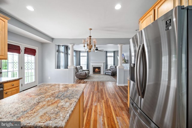 5606 Joshua Tree Cir, Fredericksburg, VA 22407 - kitchen featuring stainless steel refrigerator with ice dispenser, decorative columns, wood-type flooring, light brown cabinetry, and a lit fireplace