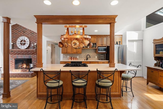 13013 Alum Springs Rd, Culpeper, VA 22701 - kitchen with appliances with stainless steel finishes, light countertops, decorative backsplash, light wood-style floors, and brown cabinetry