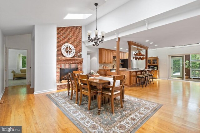 13013 Alum Springs Rd, Culpeper, VA 22701 - dining space with a brick fireplace, light wood-type flooring, baseboards, a chandelier, and high vaulted ceiling