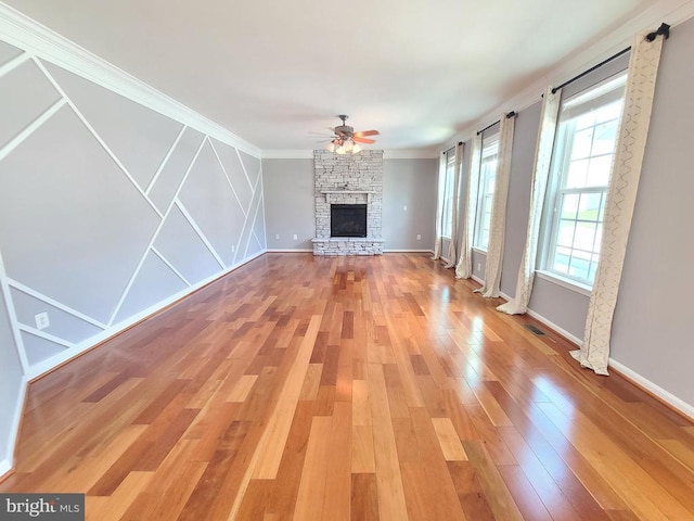 9423 Reservoir Rd, Fredericksburg, VA 22407 - unfurnished living room featuring a ceiling fan, a stone fireplace, light wood-style flooring, and crown molding