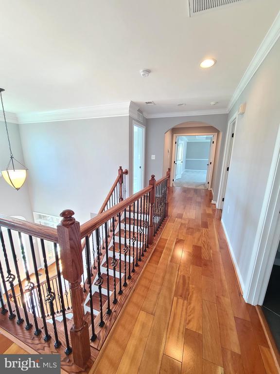 9423 Reservoir Rd, Fredericksburg, VA 22407 - hallway with arched walkways, light wood-style flooring, ornamental molding, baseboards, and an upstairs landing