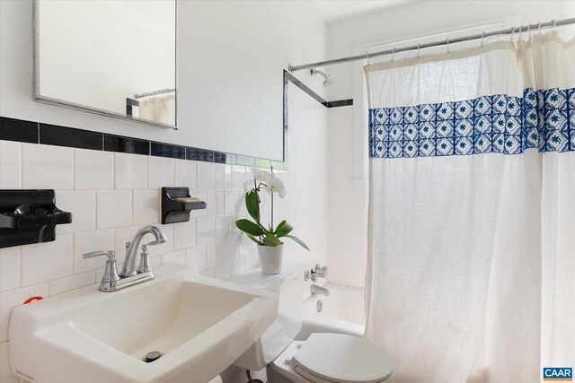 full bath with a sink, tile walls, toilet, and shower / bathtub combination with curtain
