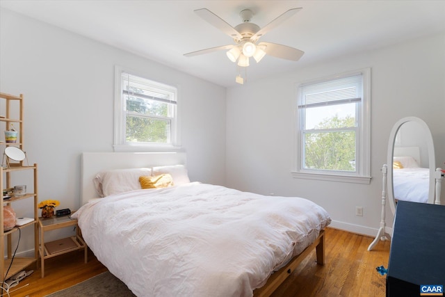 bedroom with multiple windows, wood finished floors, baseboards, and ceiling fan