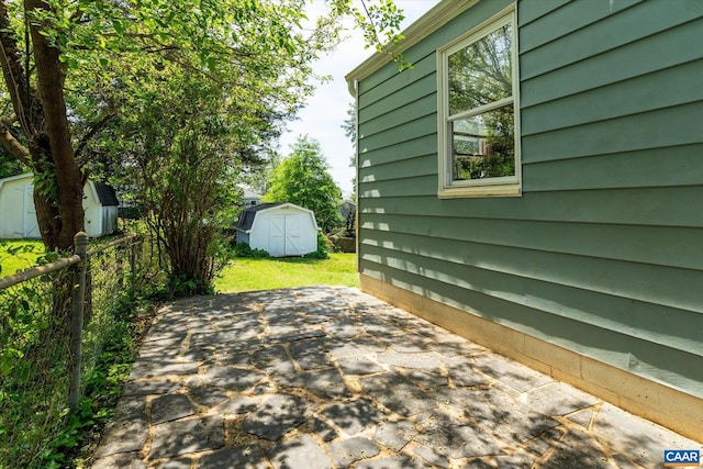 view of patio / terrace featuring a storage unit, an outbuilding, and fence