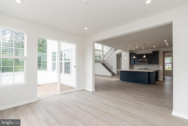 9003 Walnut Hill Rd, Fredericksburg, VA 22408 - kitchen with stainless steel microwave, light wood-style floors, light countertops, open floor plan, and decorative light fixtures