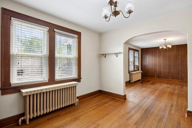 917 Chestnut Dr, Harrisonburg, VA 22801 - empty room featuring a chandelier, radiator heating unit, arched walkways, light wood-style flooring, and baseboards