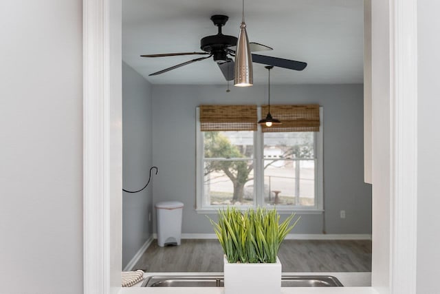 bathroom with a ceiling fan, baseboards, and wood finished floors