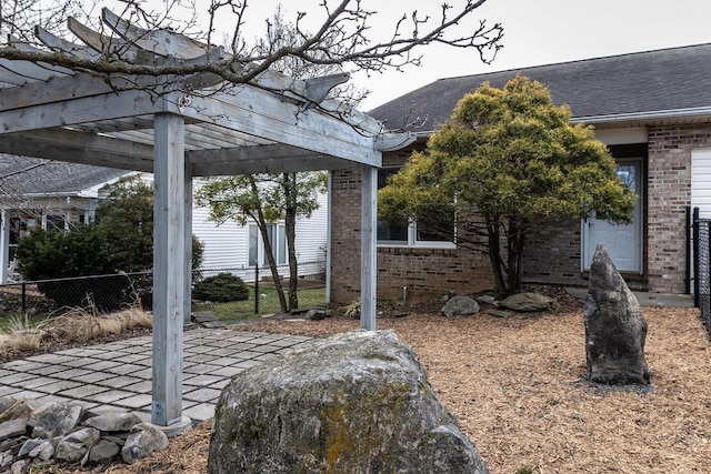 view of side of home with roof with shingles, brick siding, fence, and a pergola