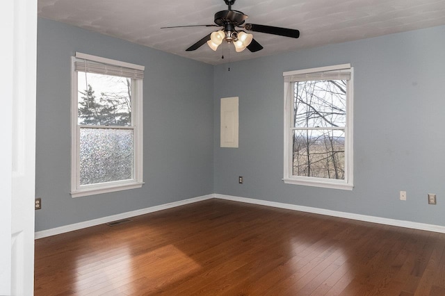 unfurnished room with baseboards, visible vents, dark wood finished floors, and a wealth of natural light