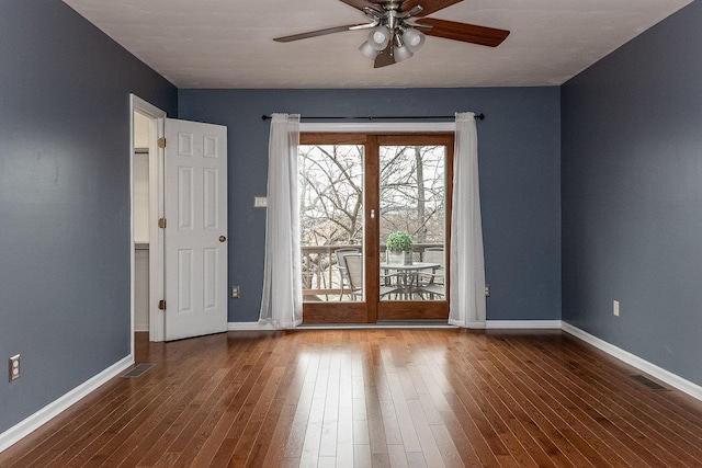 spare room featuring a ceiling fan, visible vents, baseboards, and wood finished floors