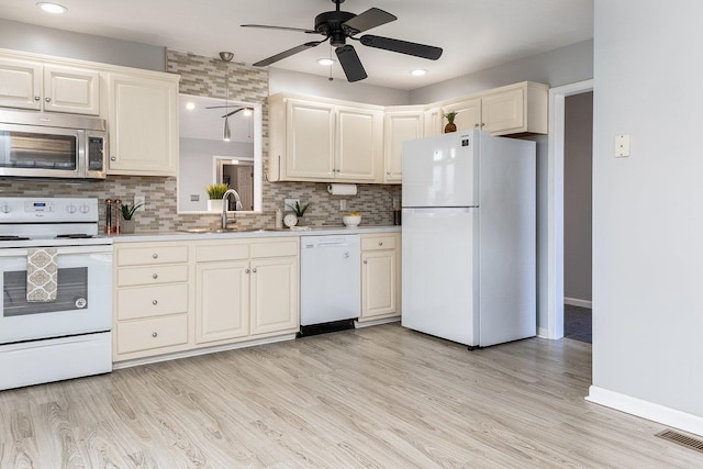 kitchen featuring white appliances, light wood finished floors, visible vents, light countertops, and a sink