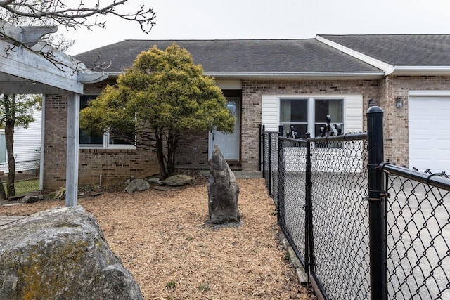 exterior space with brick siding, roof with shingles, and fence