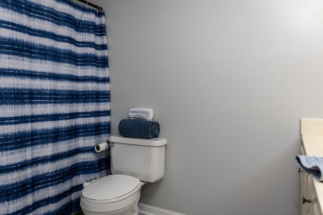 bathroom featuring toilet, baseboards, and vanity